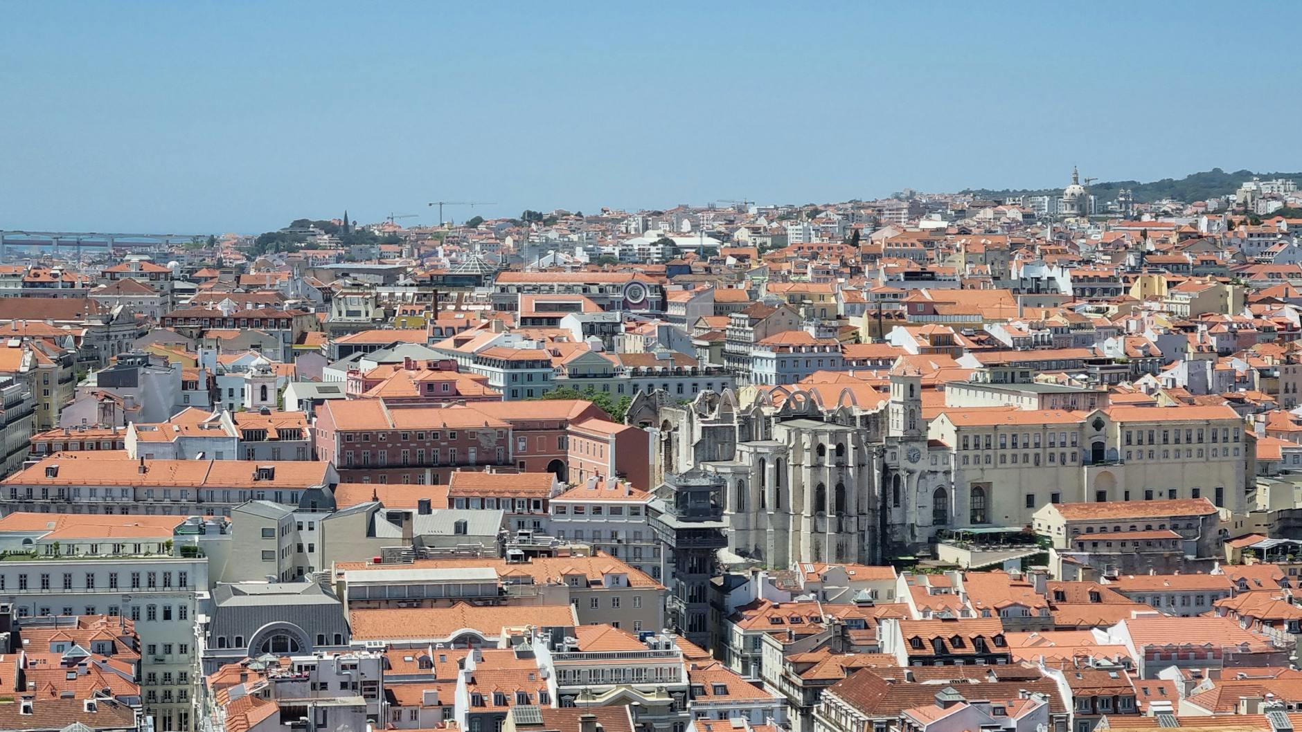Wide view of Lisbon's red rooftops and the Tagus River from a hilltop viewpoint