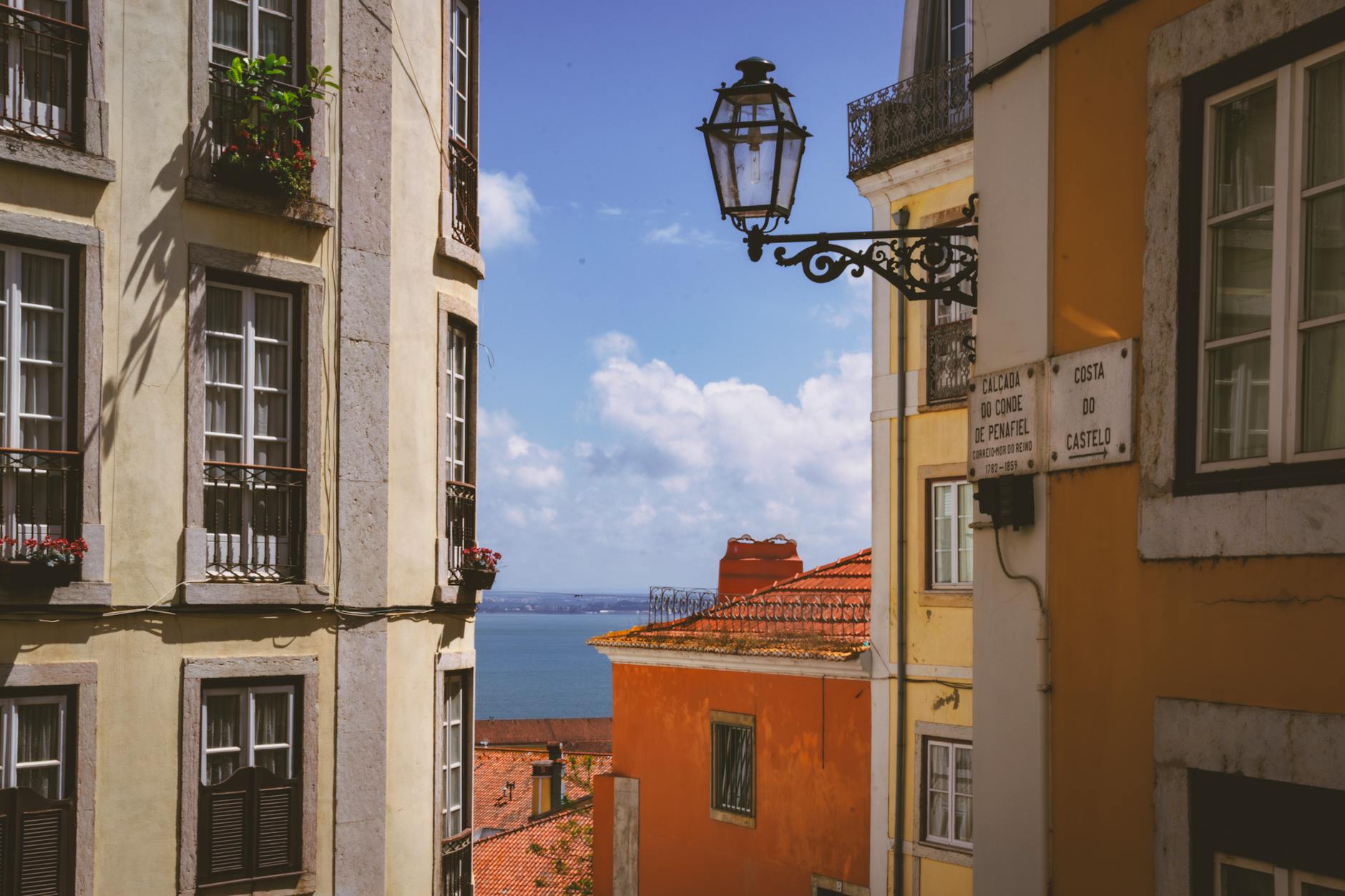 Narrow Alfama cobbled lane in Lisbon with tiled buildings and laundry