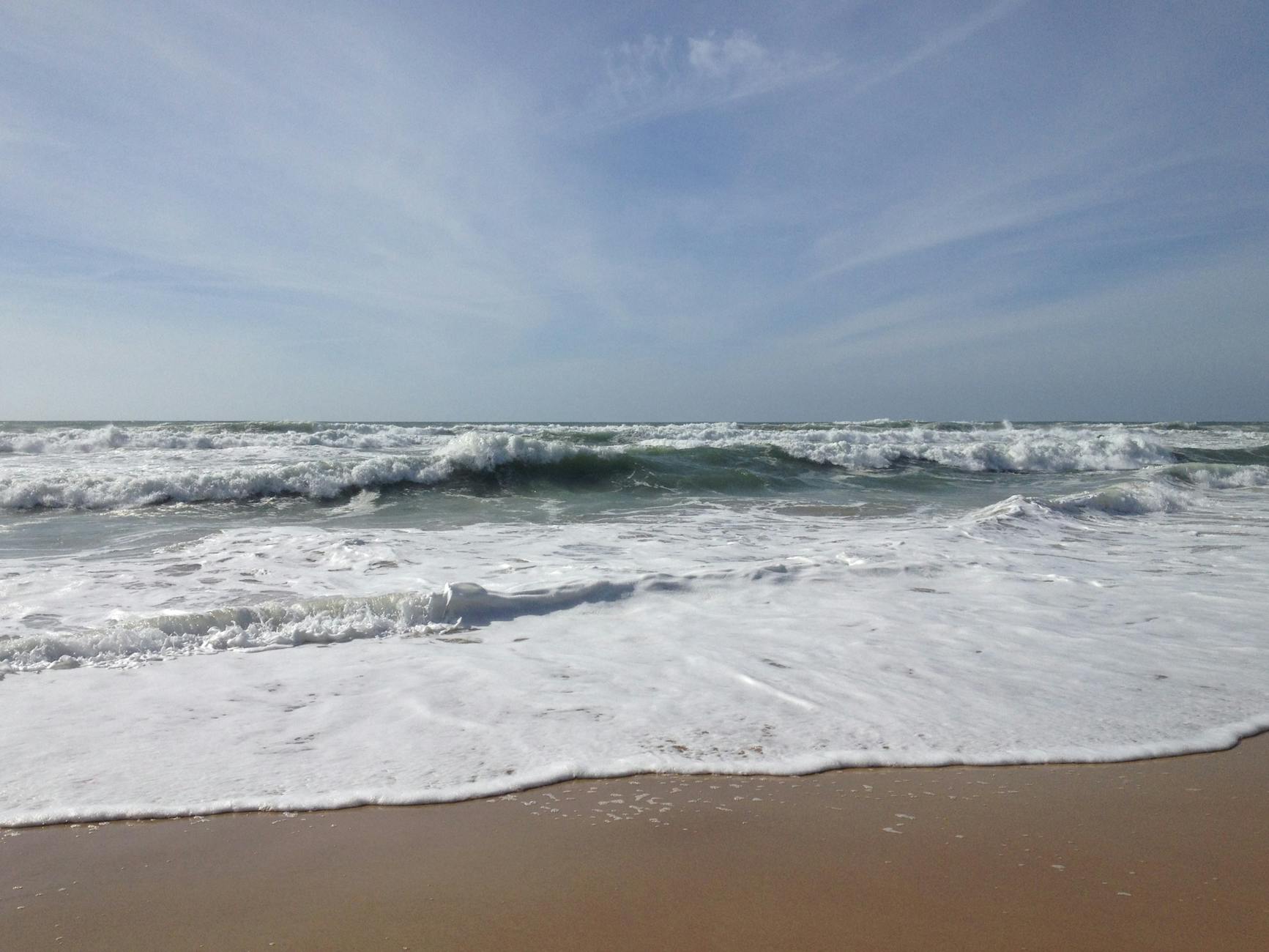 Wide sandy beach at Costa da Caparica with Atlantic surf and beach bars
