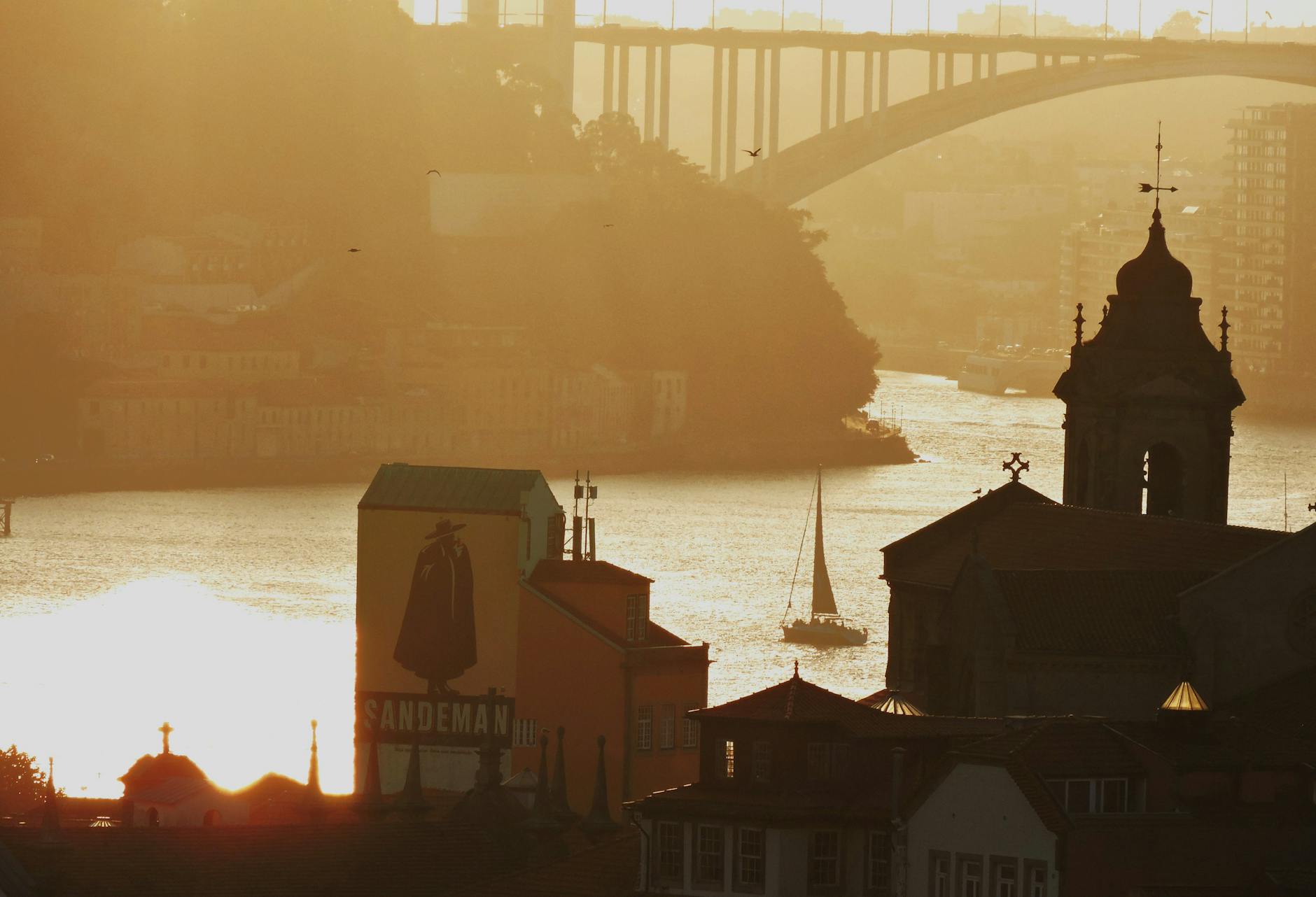 Sunset sailboat on the Tagus River with bridge silhouetted in distance
