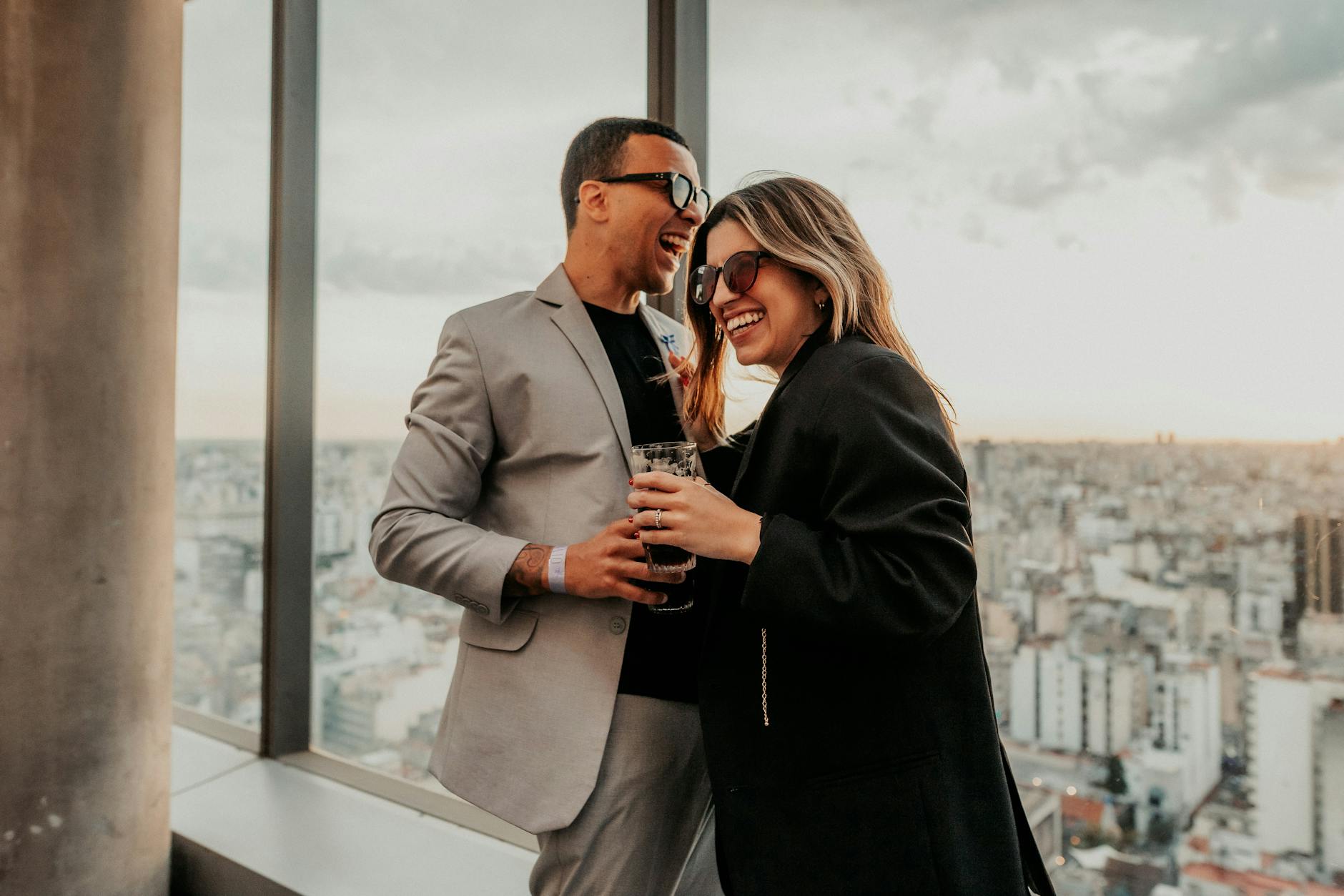 Couple enjoying drinks at a Lisbon rooftop bar at sunset over the city
