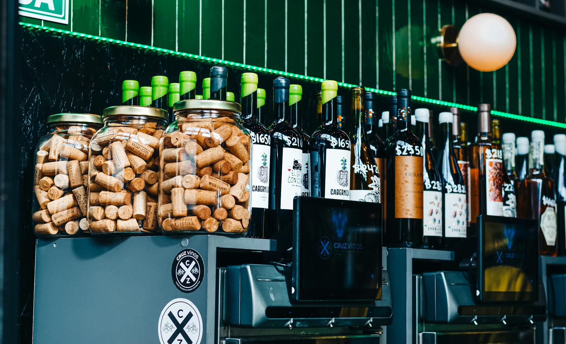 Wine glasses on a marble counter at a Lisbon wine bar with bottles displayed behind