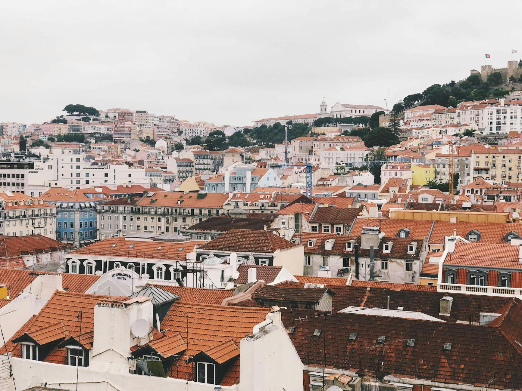 Aerial view of Lisbon's red rooftops, Tagus River, and São Jorge Castle on a hill