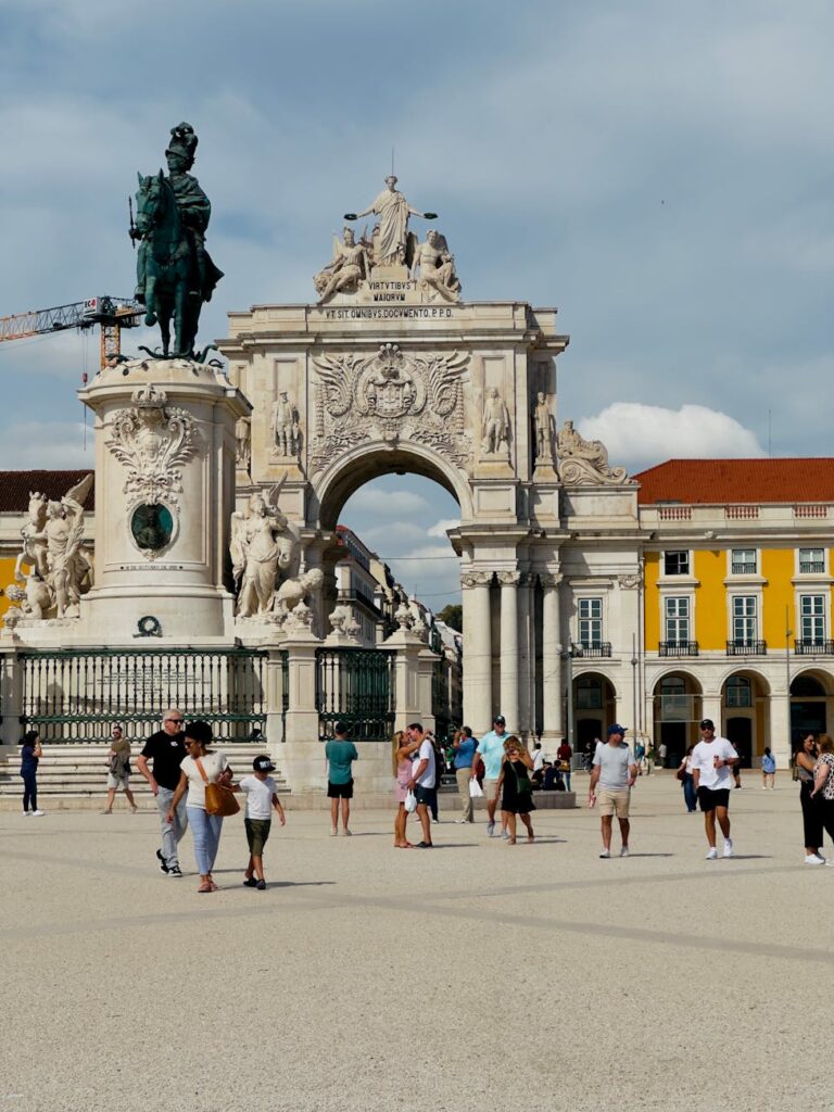 Tourists exploring Praça do Comércio with its iconic triumphal arch and equestrian statue in Lisbon