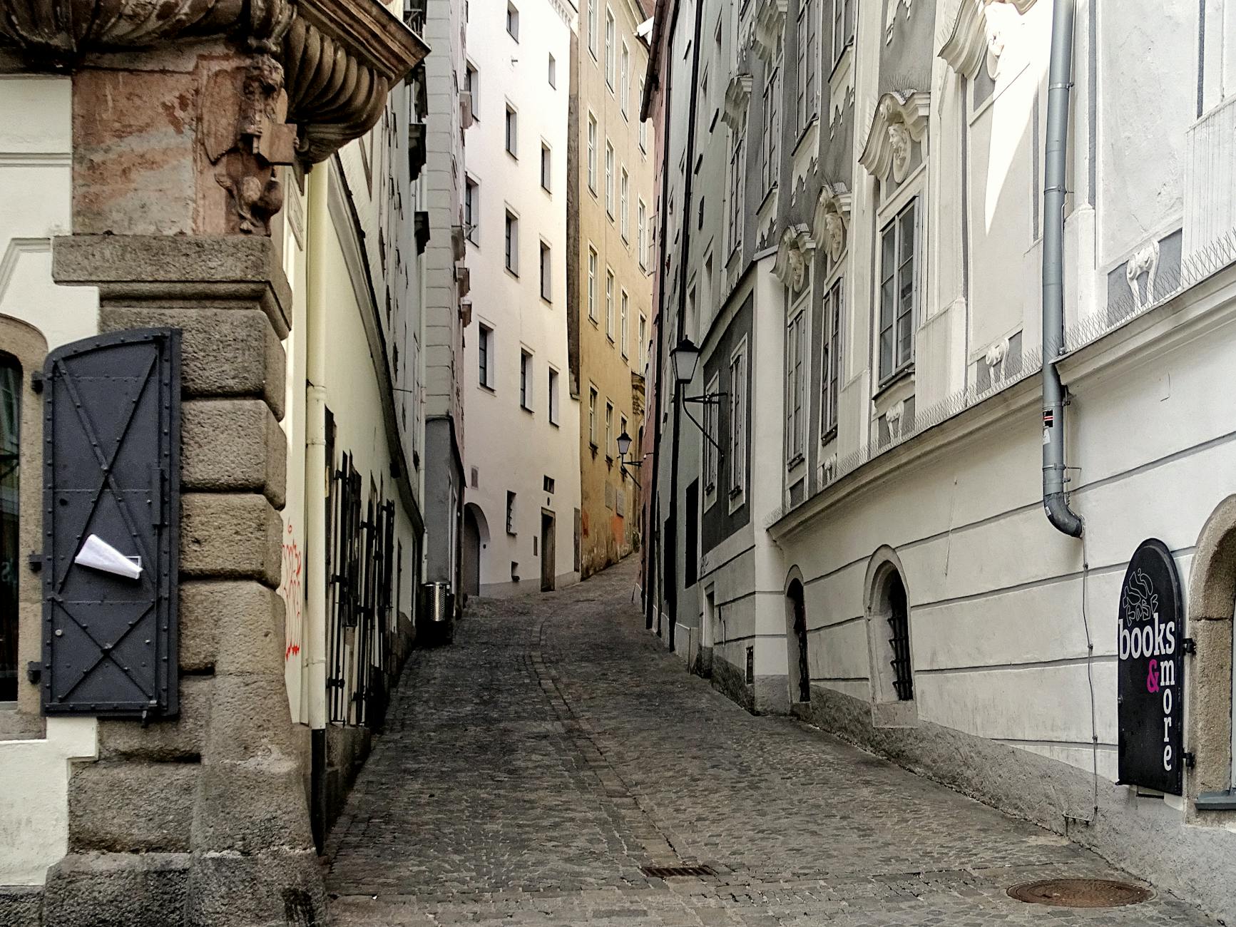 Tourist with map walking up cobblestoned narrow Alfama street with traditional tile facades