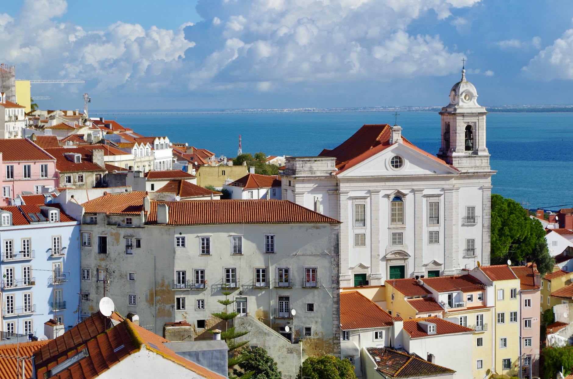 Colourful Alfama buildings with church overlooking the Tagus in Lisbon