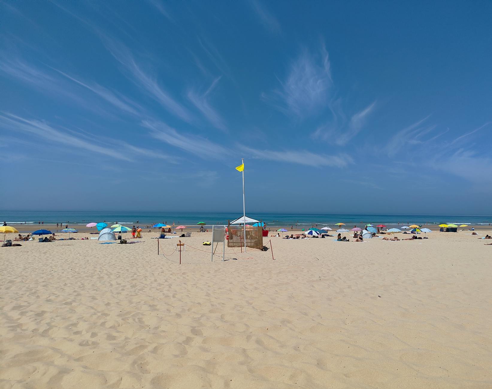 Beach umbrellas and sunbathers on a sunny day at Costa da Caparica Portugal