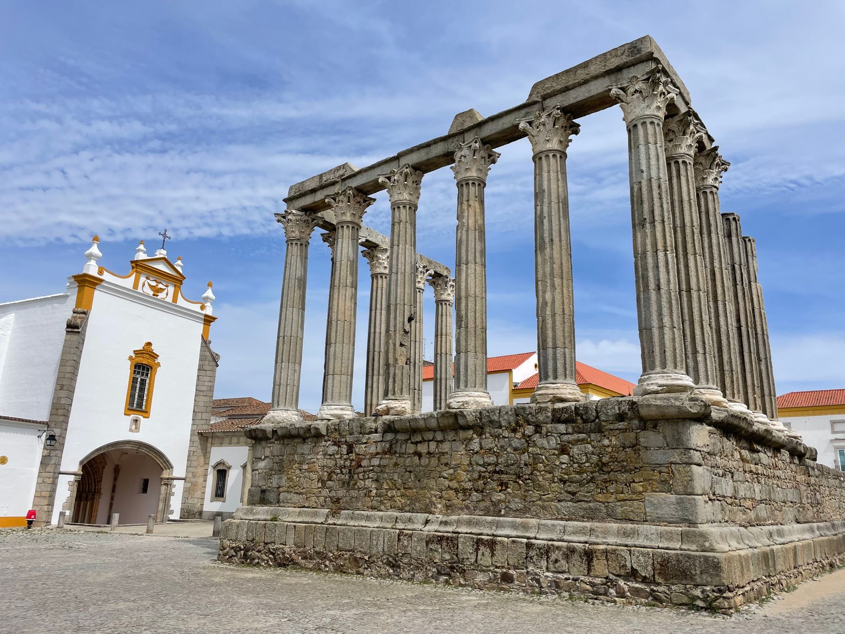 Roman Temple and Baroque church facade in Evora Portugal under blue sky