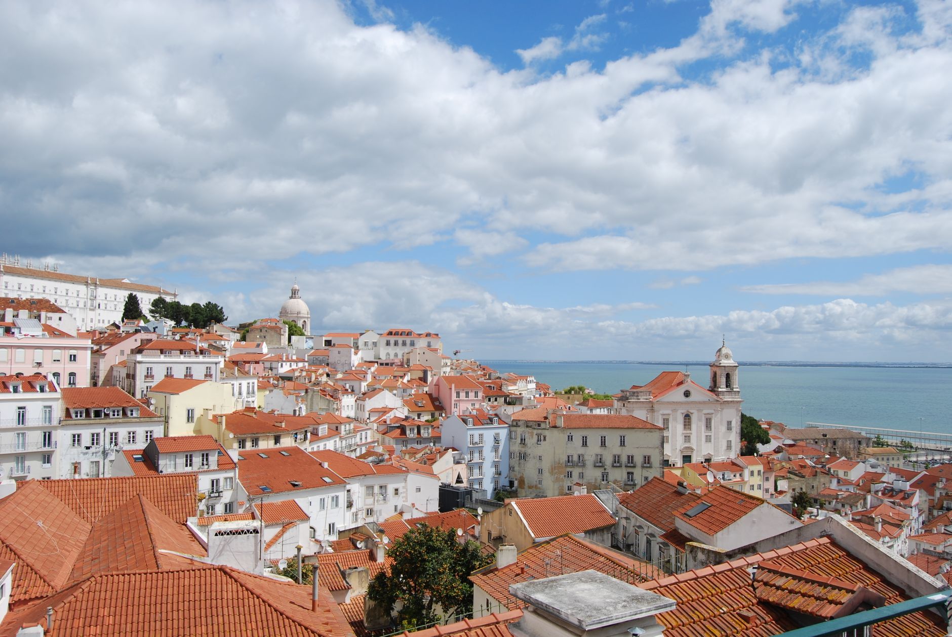 Panoramic view over Alfama district red rooftops with Tagus River in background