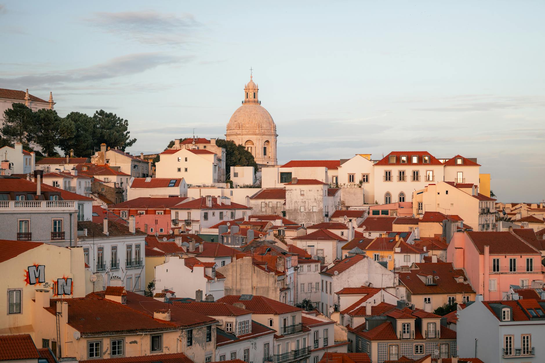 Lisbon Alfama district at sunset with historic buildings and iconic dome, view from a miradouro