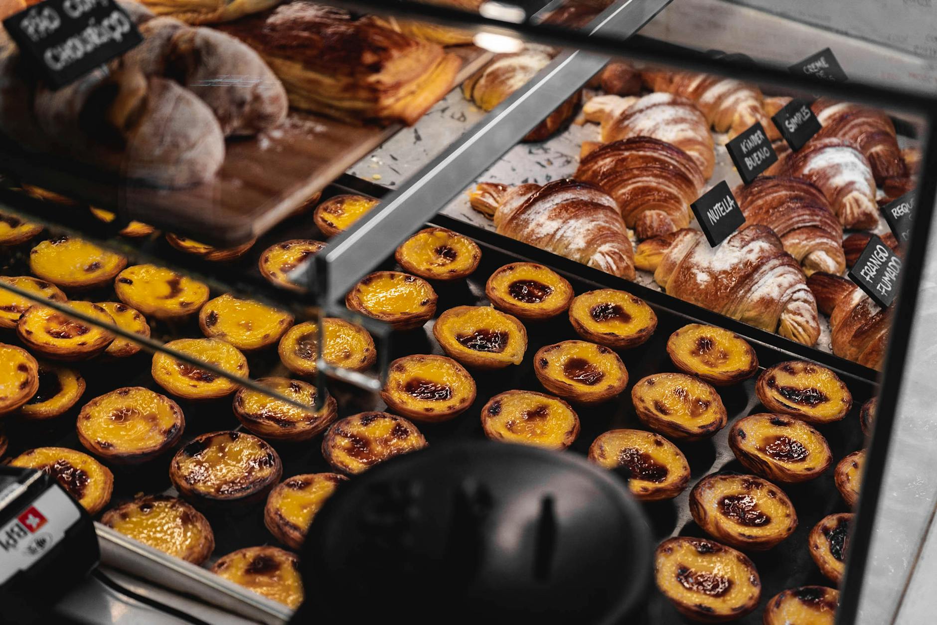 Pastéis de nata and croissants displayed in a Lisbon bakery
