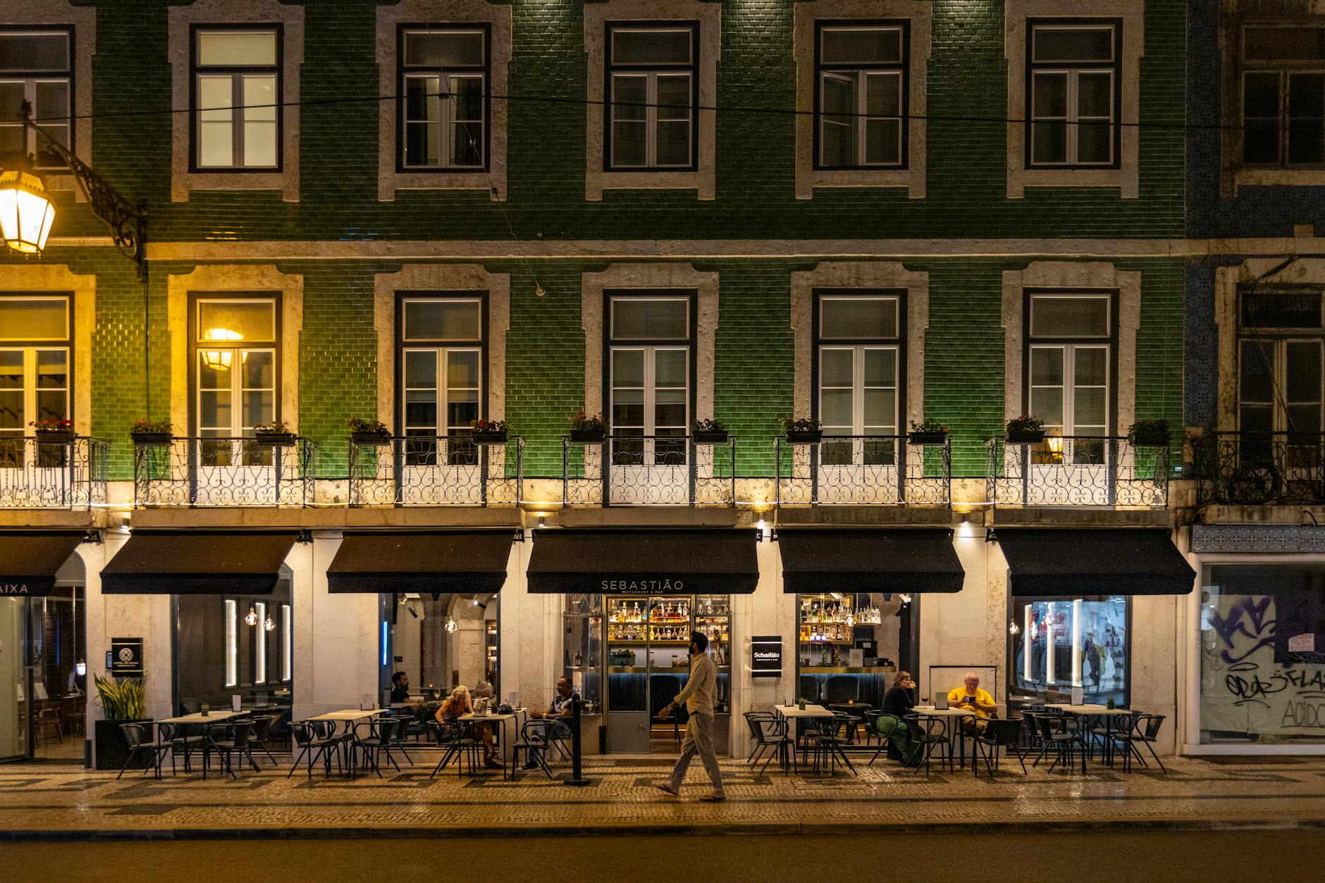 Lisbon cafe outdoor seating at night with patrons on a lively neighborhood street