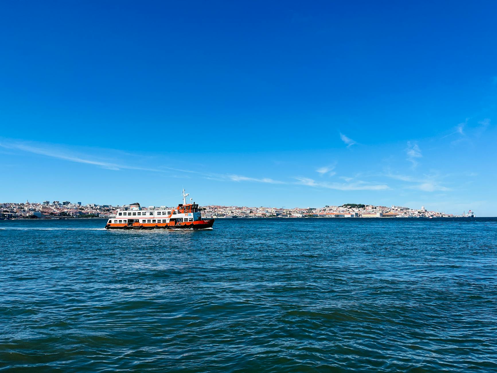 Ferry crossing the Tagus River with Lisbon's historic skyline in the background