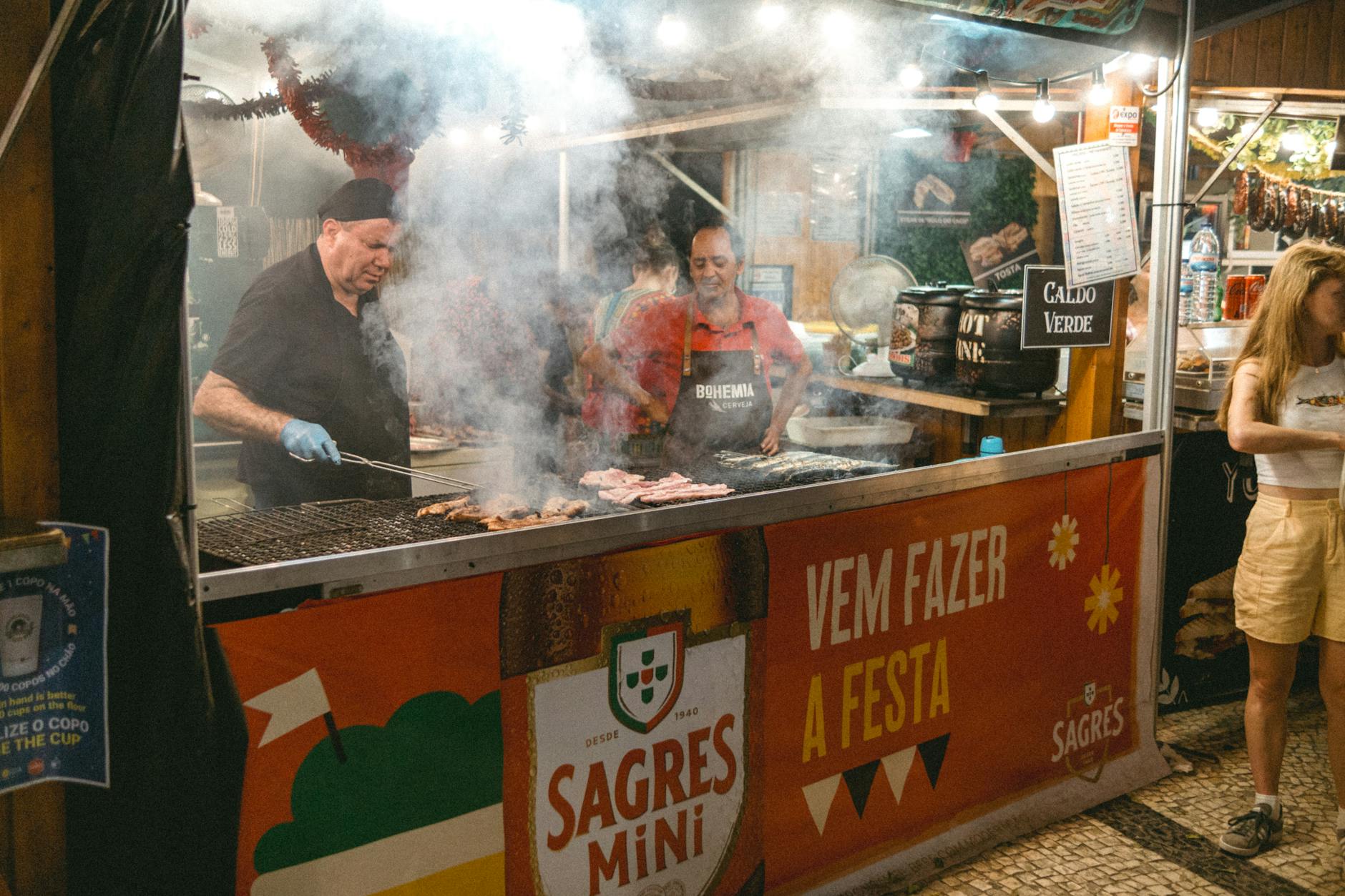 Street food vendors grilling meats at a lively night market in Lisbon Portugal