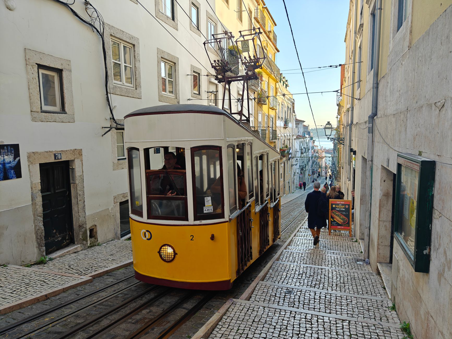 Yellow Lisbon funicular ascending steep cobbled street in historic district