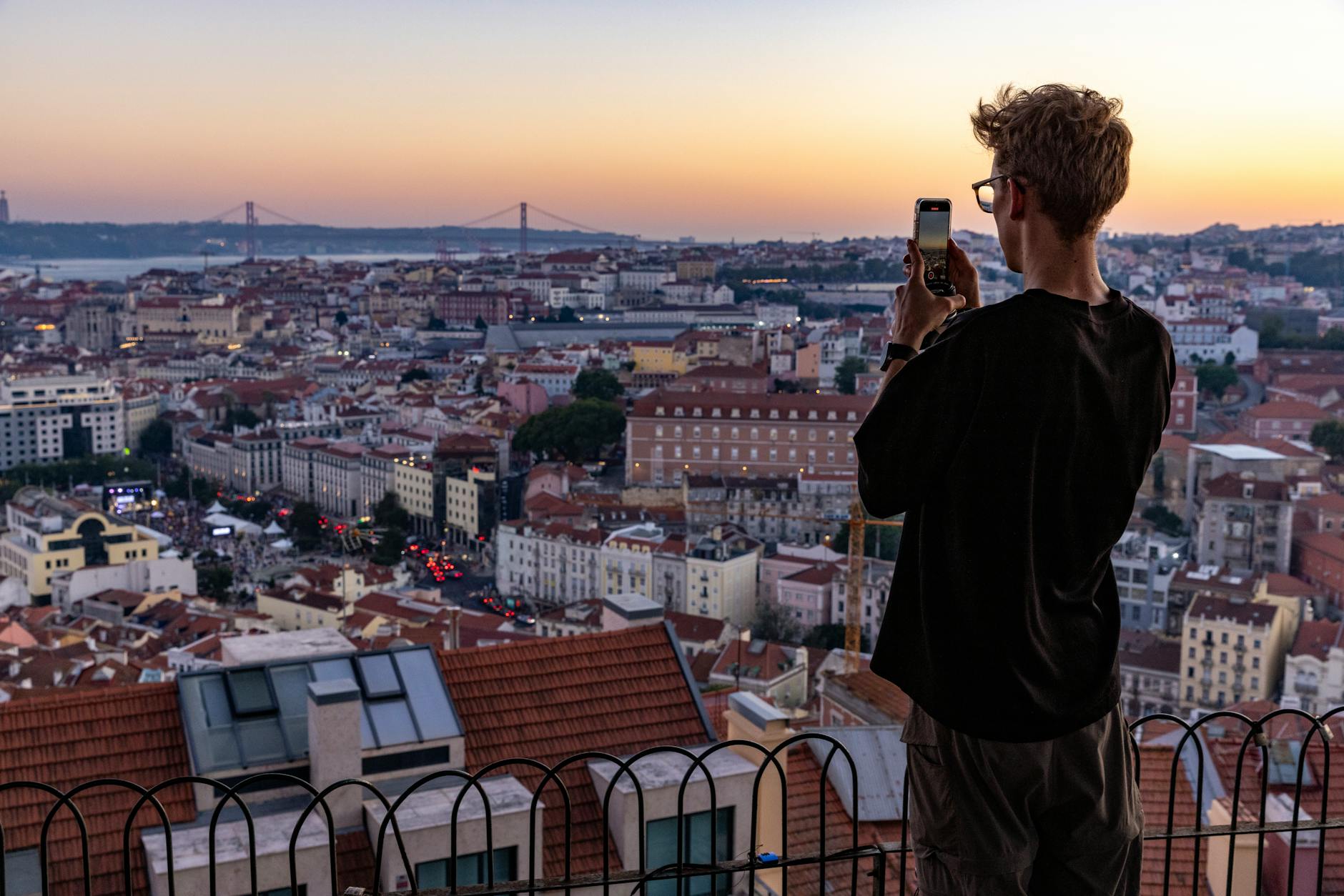 Photographer capturing the golden sunset over Lisbon's rooftops from a hilltop miradouro