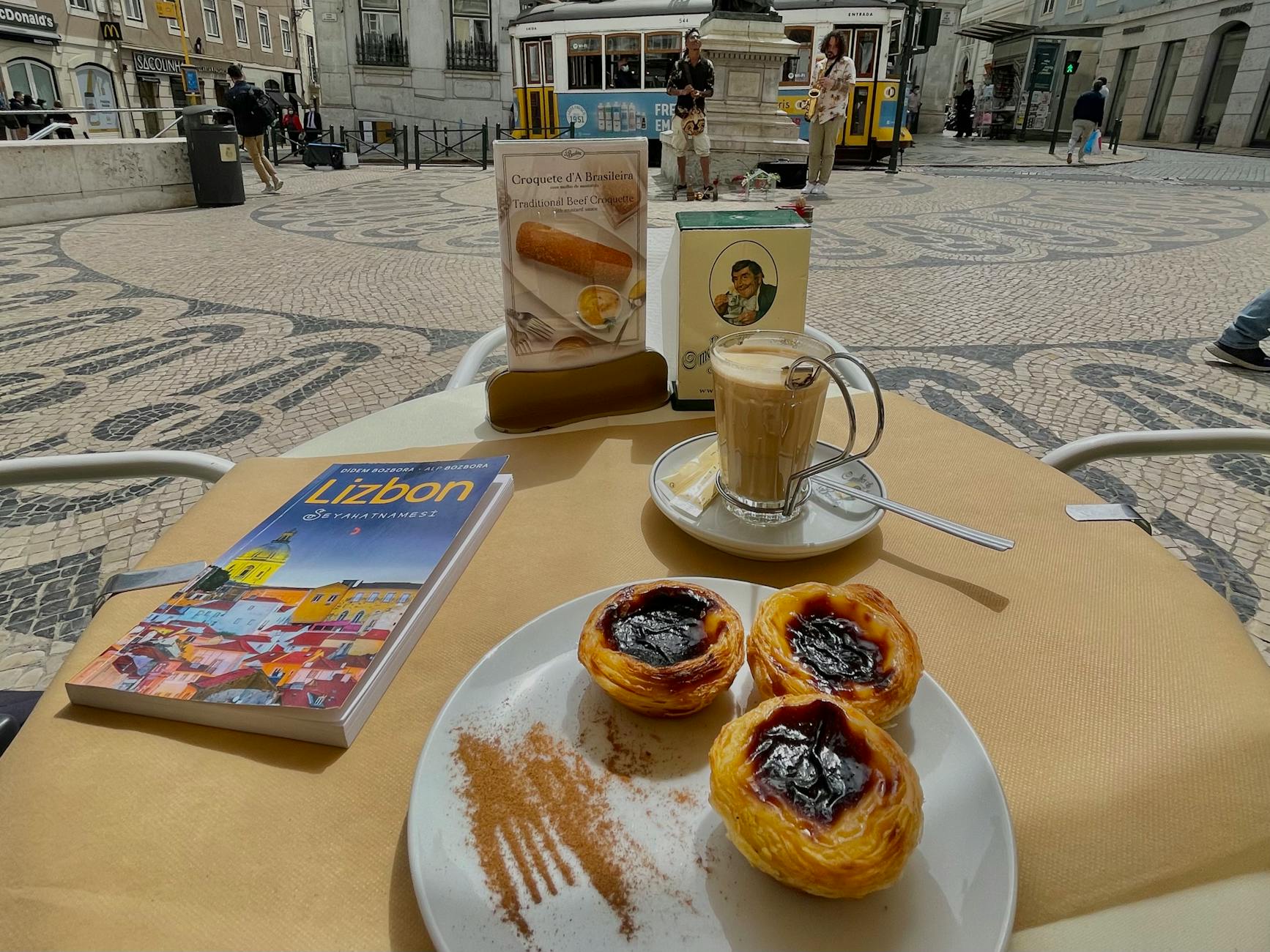 Pastéis de nata and coffee at a Lisbon café with tram visible through the window