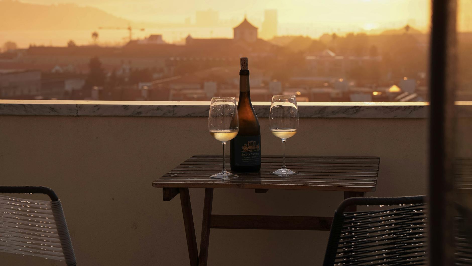 Rooftop terrace view across Lisbon rooftops toward the Tagus River at sunset