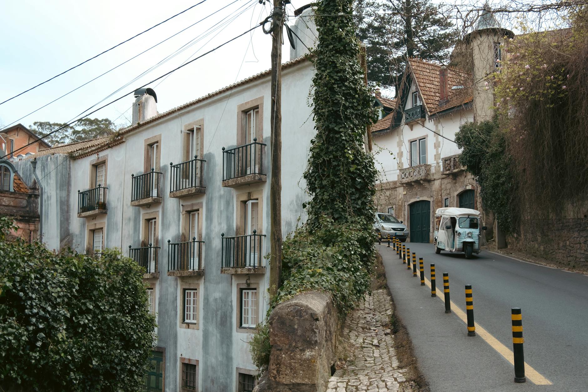 Tuk tuk on a narrow historic Lisbon street with tiled building facades