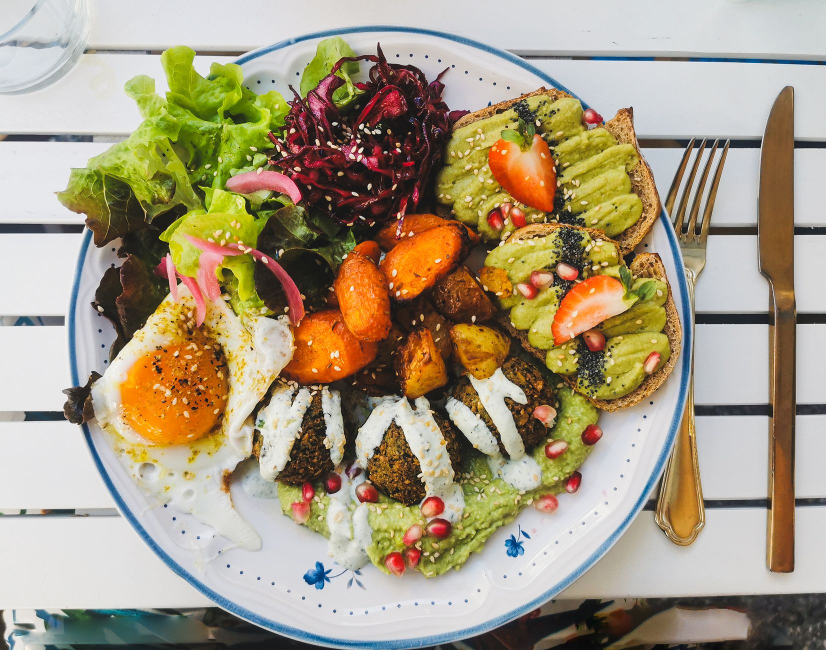 Vegan brunch plate with falafel avocado toast and roasted vegetables at a Lisbon cafe