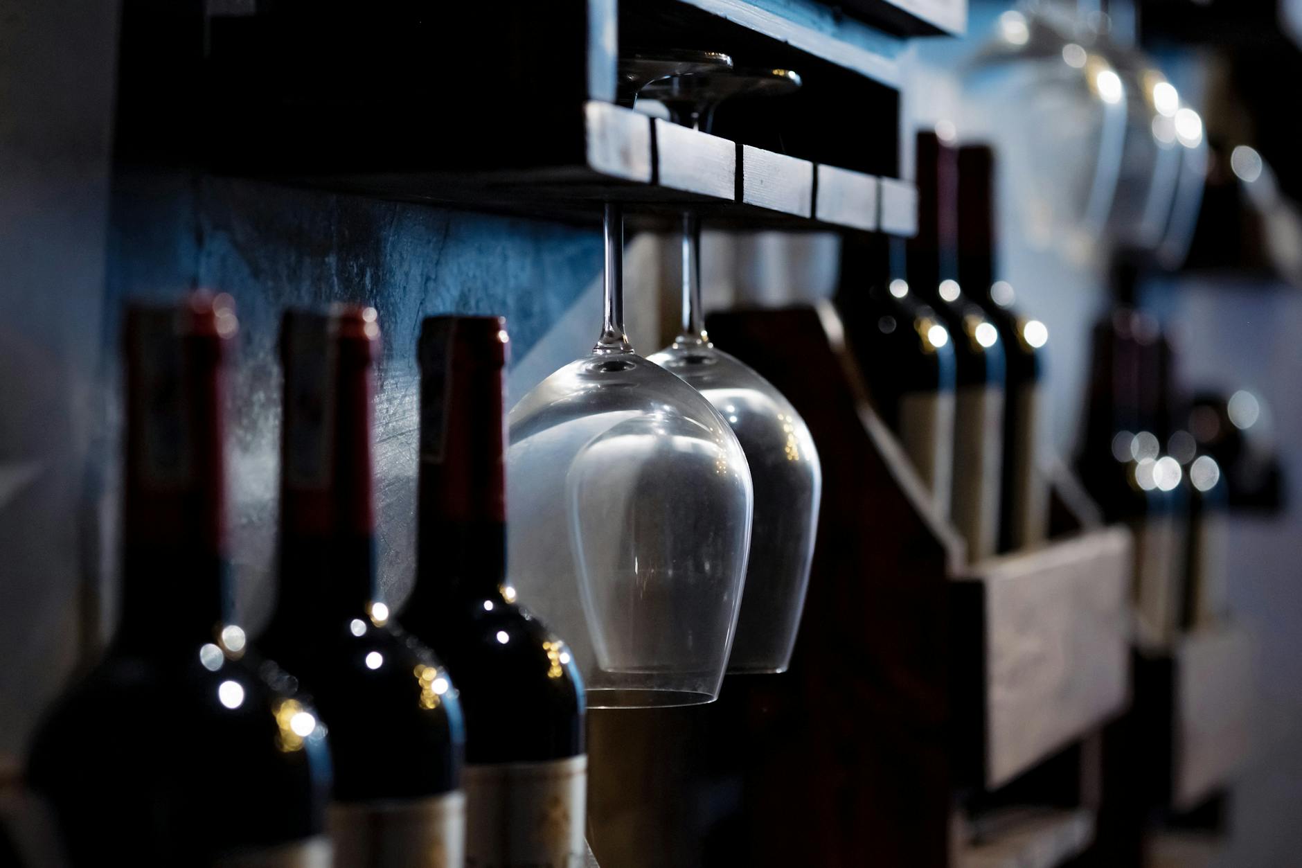 Wine bottles and glasses on wooden shelves in a cozy Lisbon wine cellar bar