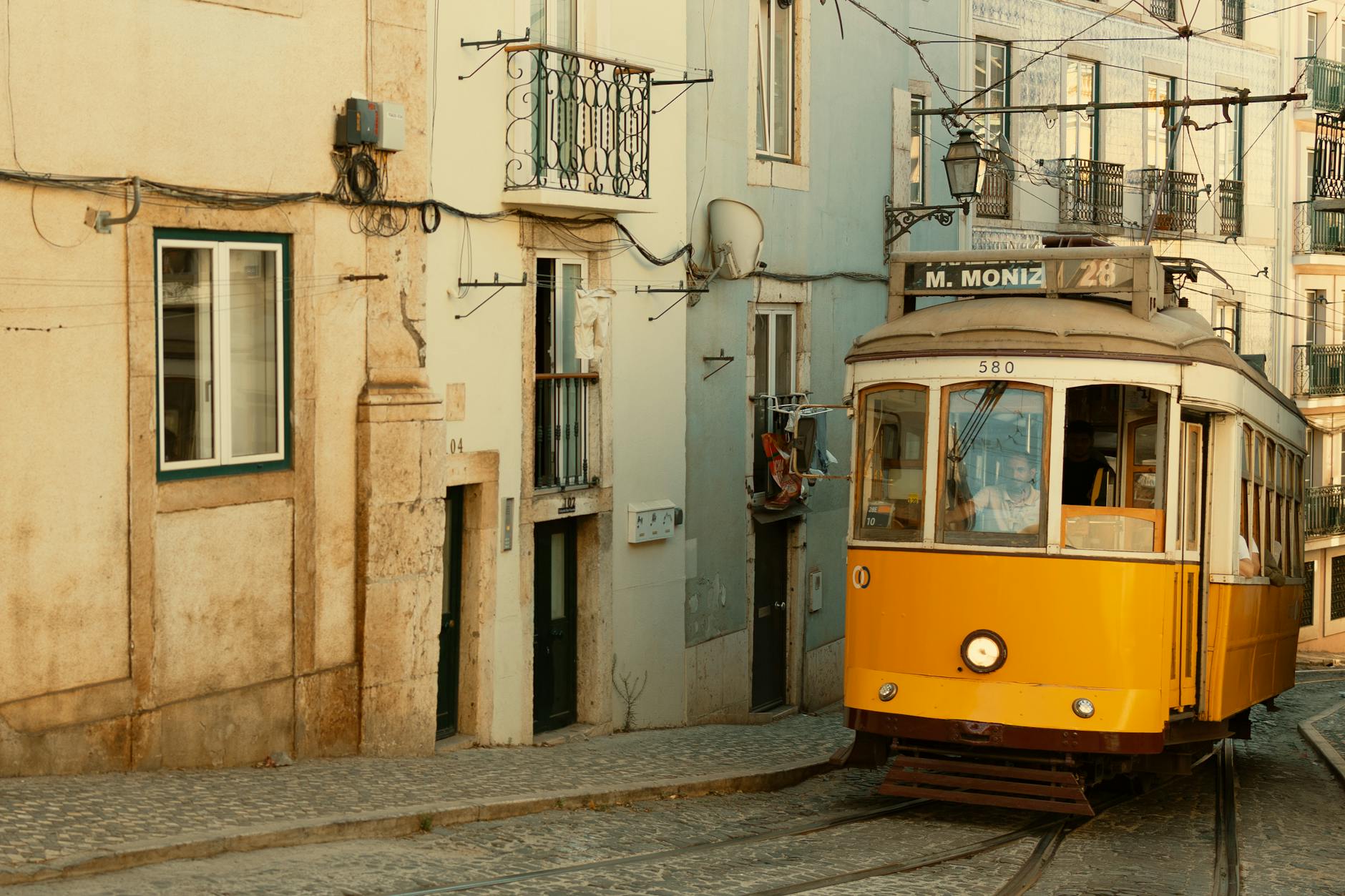 Classic yellow Lisbon tram on cobblestone street in historic city centre