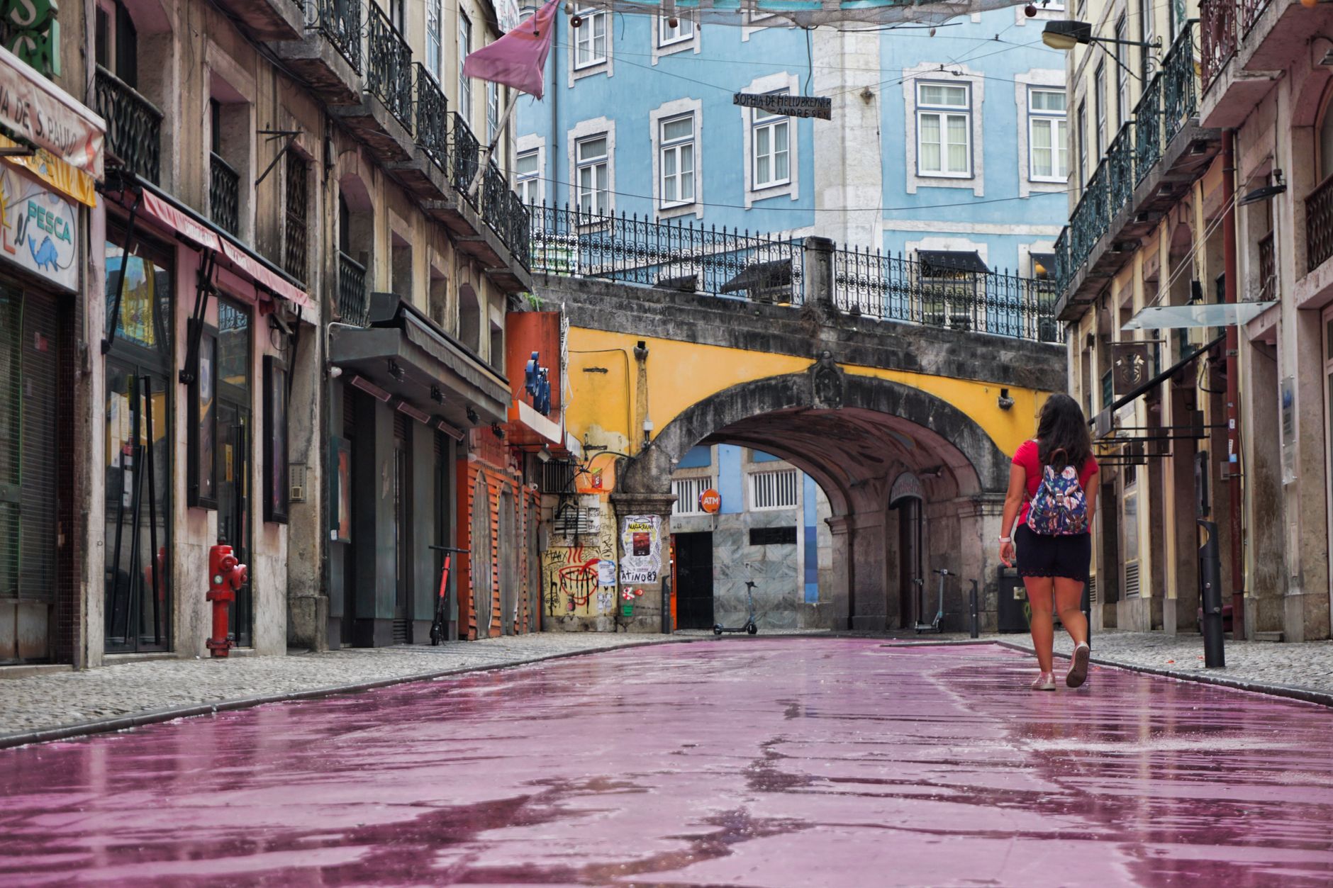 Woman walking on the famous pink-painted cobblestones of Rua Nova do Carvalho, Pink Street Lisbon