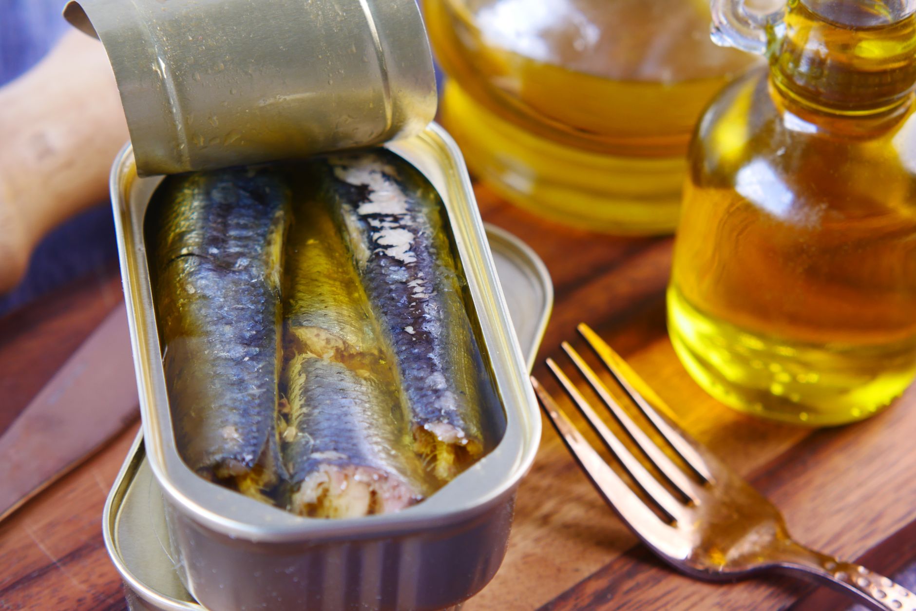 Close-up of Portuguese canned sardines in olive oil with a fork on wooden surface