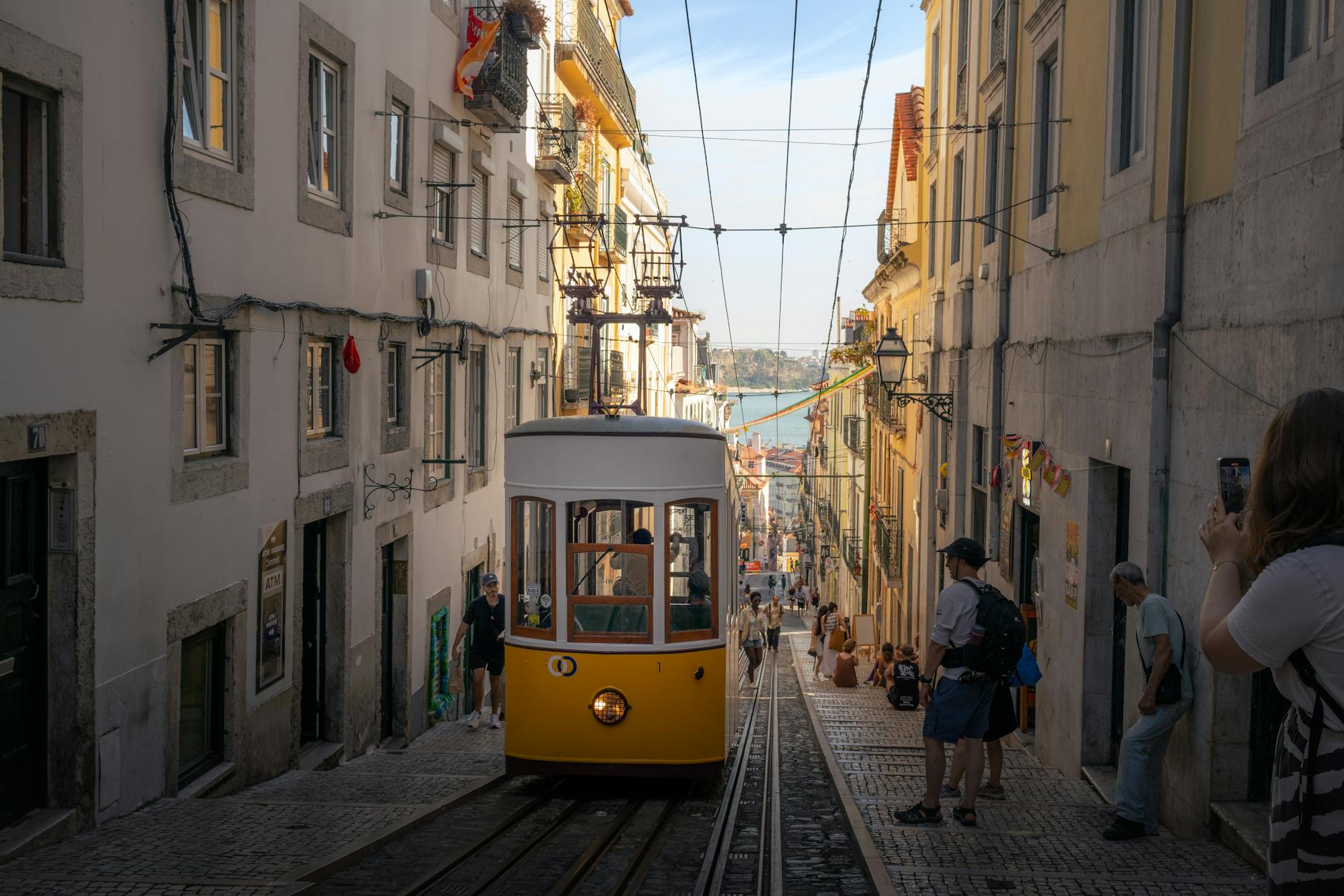 Classic yellow Tram 28 climbing a steep hill in Lisbon — the heritage tram has run this route since 1914