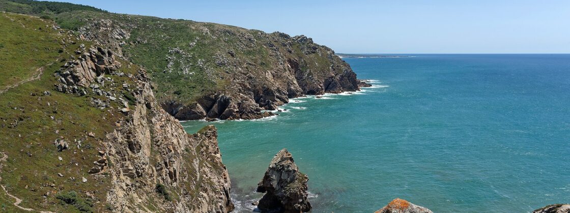 Cliffs at Cabo da Roca falling into a turquoise Atlantic bay, with a sea stack below and a footpath along the headland
