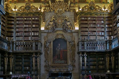 The gilded baroque interior of the Biblioteca Joanina at the University of Coimbra with tiered bookshelves