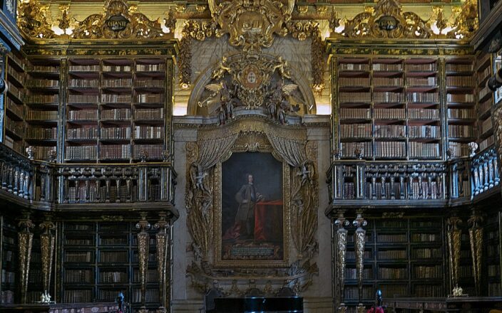 The gilded baroque interior of the Biblioteca Joanina at the University of Coimbra with tiered bookshelves