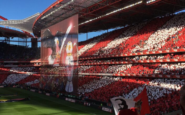 Packed red and white stands at the Estadio da Luz with a giant eagle tifo banner before a Benfica match