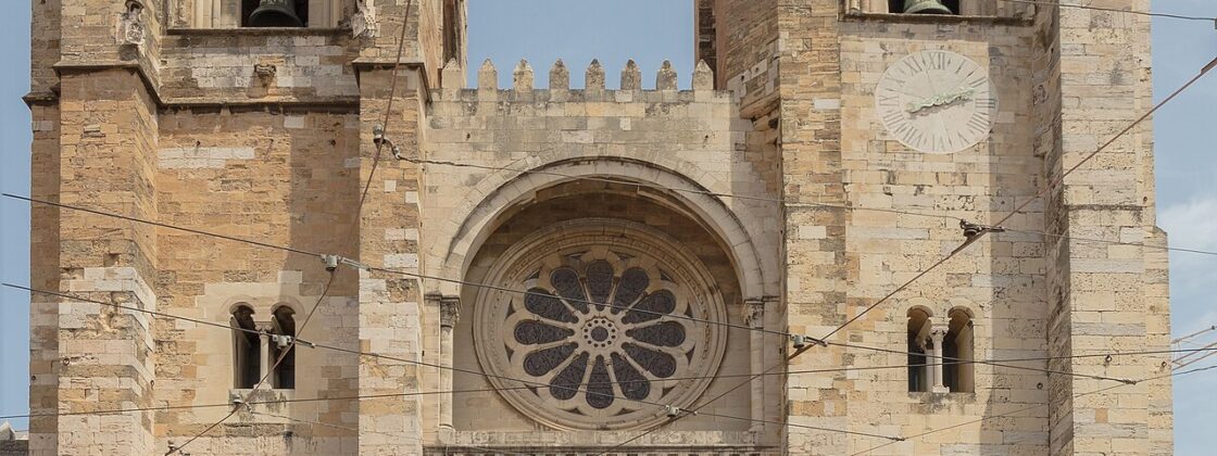 West front of Lisbon Cathedral with two crenellated bell towers and the rose window