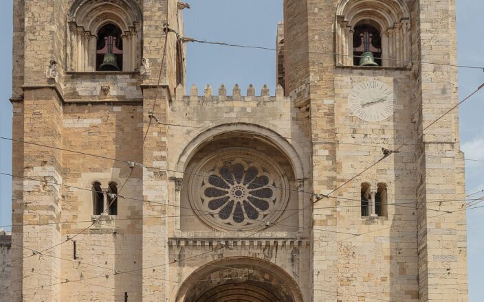 West front of Lisbon Cathedral with two crenellated bell towers and the rose window