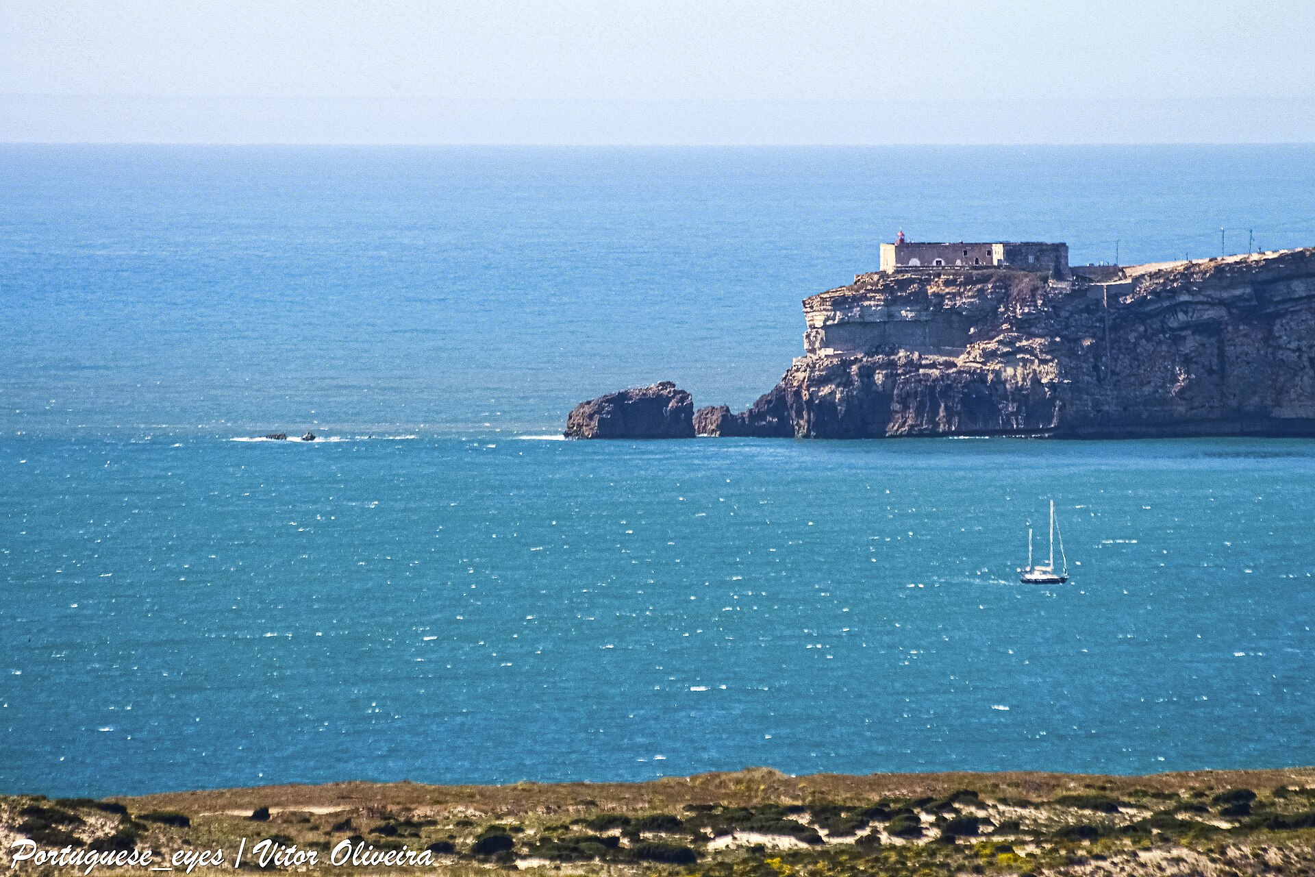 The Forte de São Miguel Arcanjo and its lighthouse on the headland at Nazaré above a calm blue sea