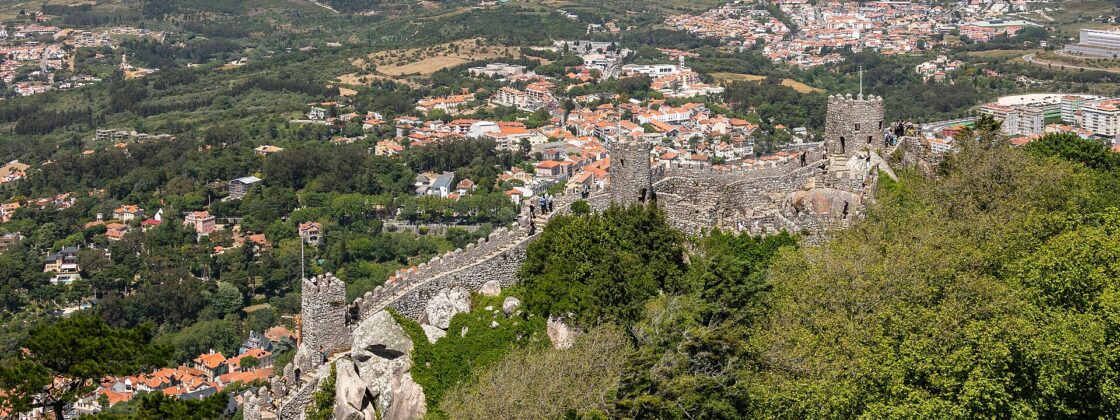 The crenellated walls of the Castelo dos Mouros running along the Sintra ridge, with the town and the coastal plain far below