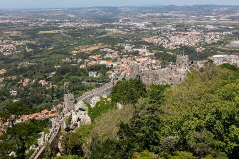The crenellated walls of the Castelo dos Mouros running along the Sintra ridge, with the town and the coastal plain far below