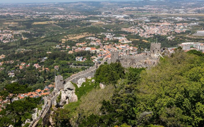 The crenellated walls of the Castelo dos Mouros running along the Sintra ridge, with the town and the coastal plain far below
