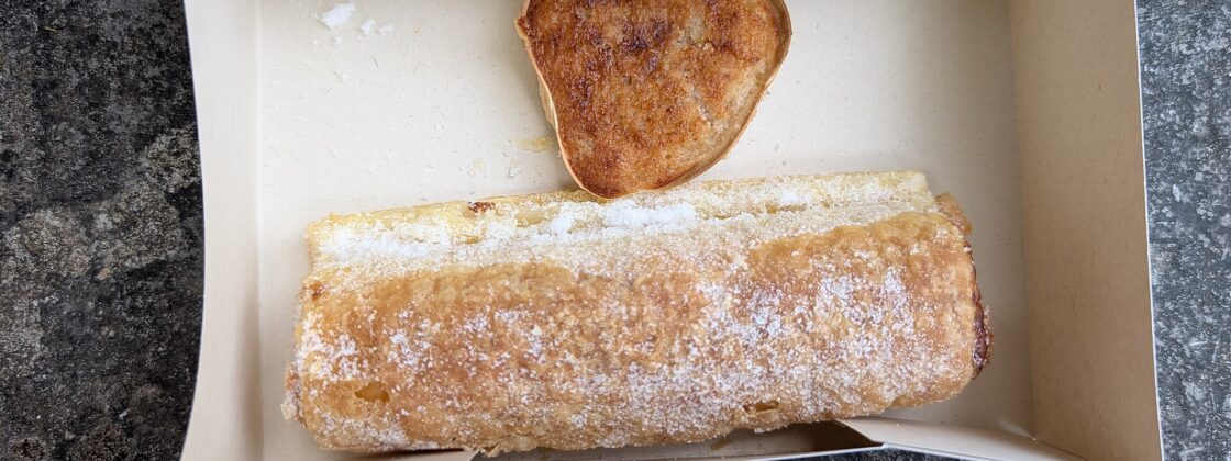 A sugar-dusted travesseiro and a queijada de Sintra in a paper pastry box