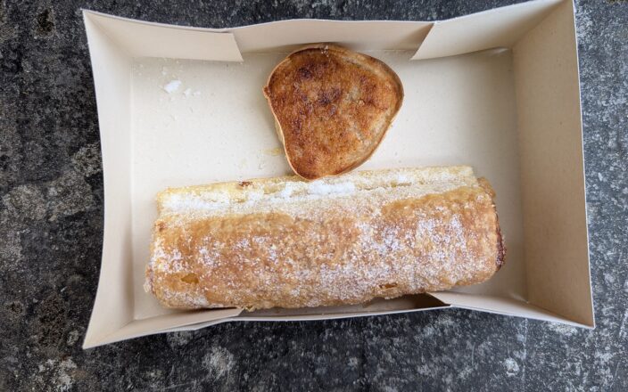 A sugar-dusted travesseiro and a queijada de Sintra in a paper pastry box