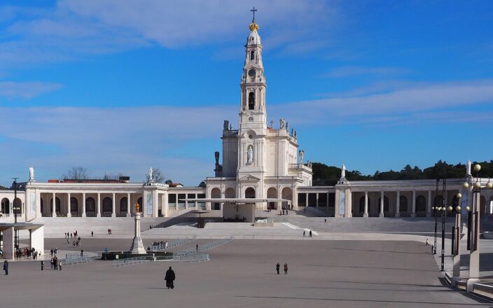 The Basilica of Our Lady of the Rosary towers above Fátima’s broad esplanade, with visitors scattered across the square.