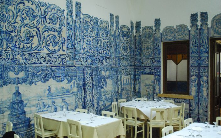 Blue and white azulejo panels surround tables set with white cloths and wine glasses at Casa do Alentejo in Lisbon.