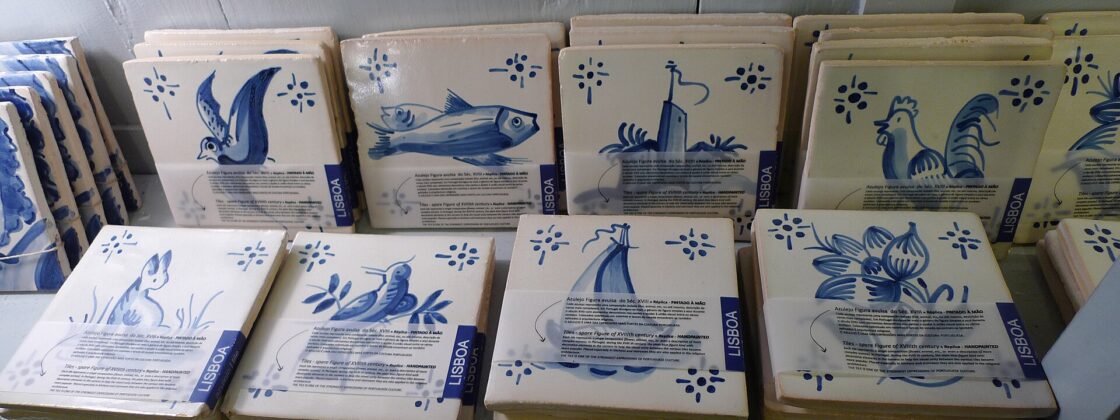 Blue-and-white souvenir tiles in a Lisbon shop depict birds, fish and flowers, with labels identifying hand-painted replicas.