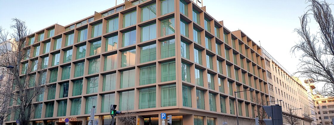 Lumen Hotel in Lisbon occupies a street corner, with tall windows and its name displayed above the roof.