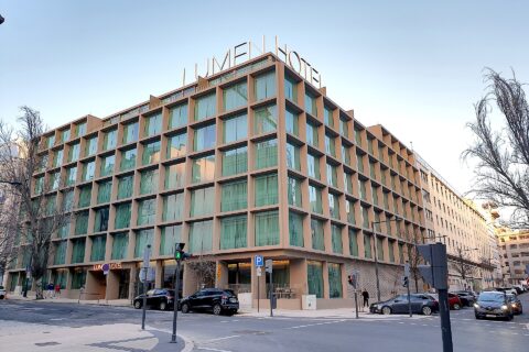 Lumen Hotel in Lisbon occupies a street corner, with tall windows and its name displayed above the roof.