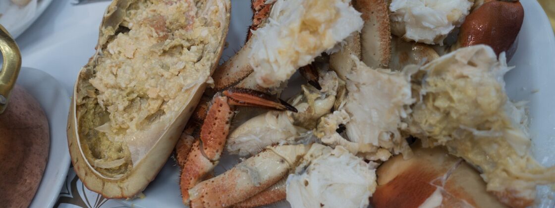 An opened crab and cracked claws cover a white platter at Cervejaria Ramiro in Lisbon, with bread beside it.
