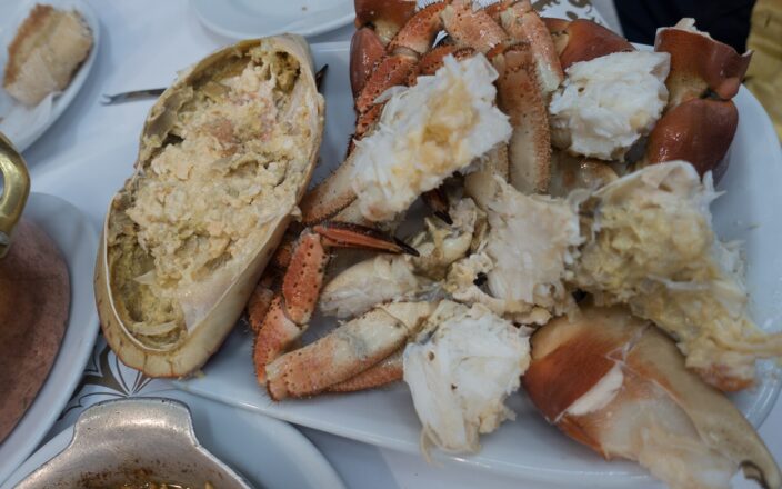 An opened crab and cracked claws cover a white platter at Cervejaria Ramiro in Lisbon, with bread beside it.