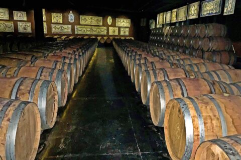 Rows of wine barrels fill Bacalhôa’s cellar in Azeitão, with decorative Portuguese tile panels lining the walls above them.
