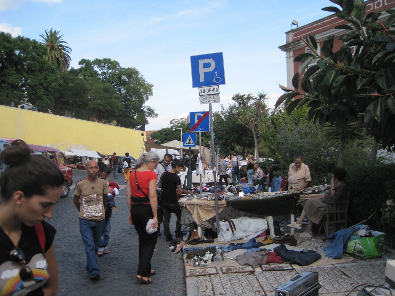 Shoppers pass glassware, framed pictures and clothing spread on the cobbled pavement at Lisbon’s Feira da Ladra.
